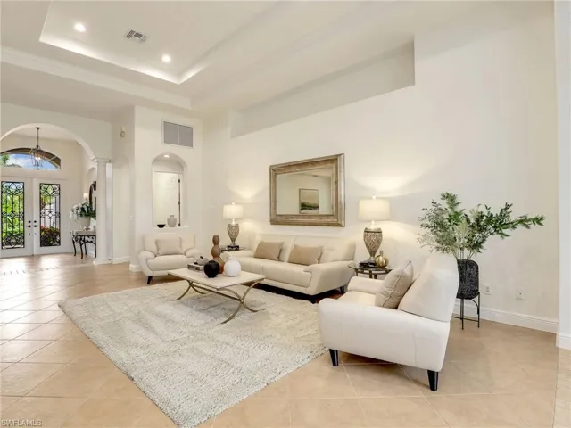 Tiled living room with a raised ceiling, a high ceiling, and french doors