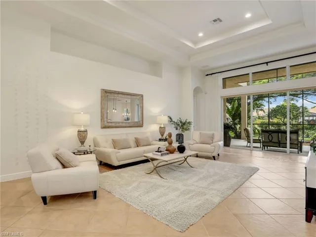 Living room featuring light tile patterned flooring, a high ceiling, and a tray ceiling