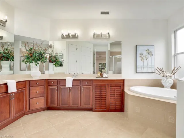 Bathroom featuring tile patterned floors, vanity, and plus walk in shower