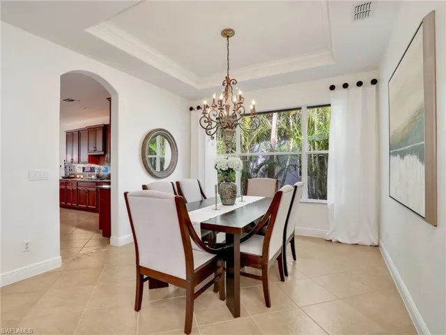 Tiled dining area with a chandelier, a raised ceiling, and crown molding