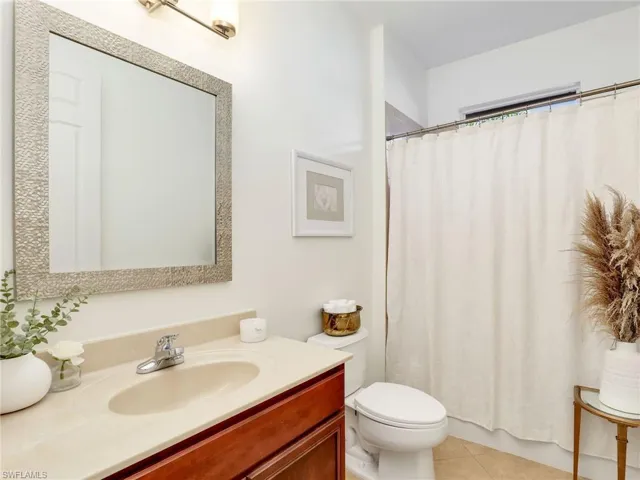 Bathroom featuring curtained shower, tile patterned flooring, vanity, and toilet