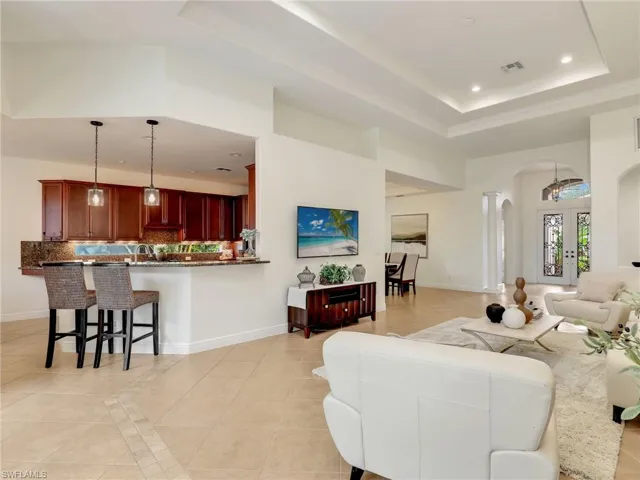 Living room with a tray ceiling, french doors, and light tile patterned floors