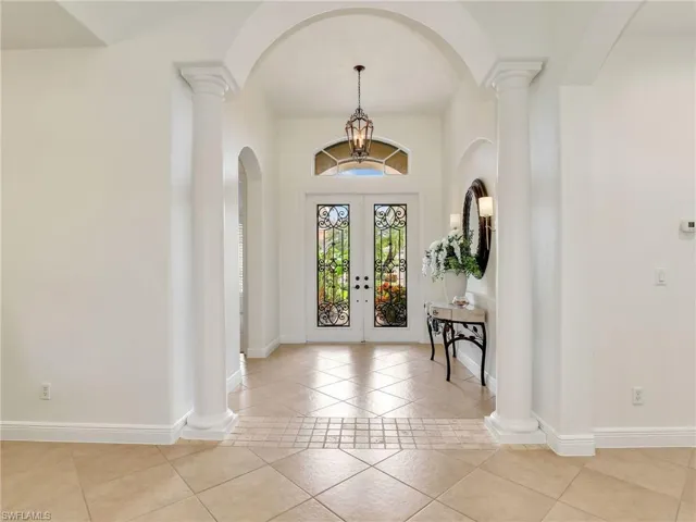 Tiled entrance foyer with a chandelier and french doors
