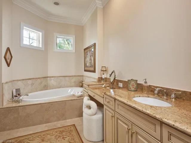 Bathroom with vanity, a garden tub, ornamental molding, and light tile patterned flooring