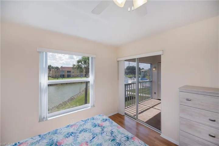 Bedroom featuring a ceiling fan, access to outside, wood finished floors, and a water view