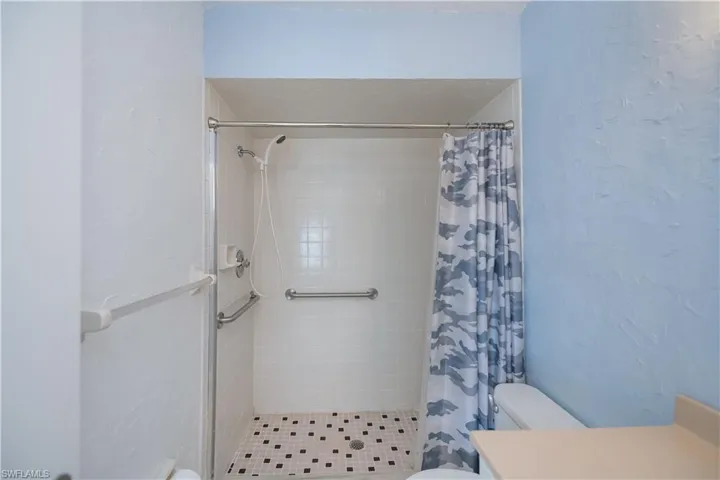 Bathroom with a textured wall, vanity, and a stall shower