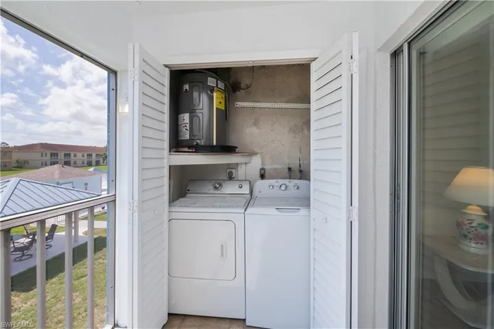 Laundry area featuring water heater, healthy amount of natural light, and washing machine and dryer