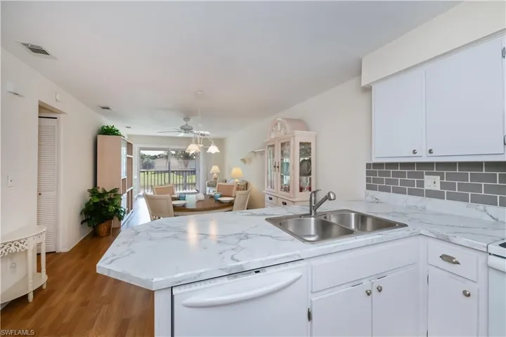 Kitchen with white dishwasher, light countertops, ceiling fan, and white cabinets