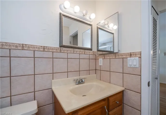 Bathroom featuring vanity, tile walls, and wainscoting