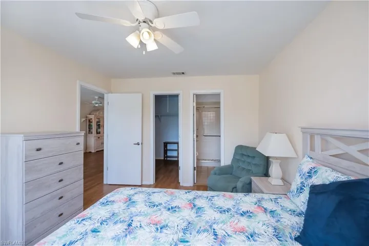 Bedroom with a spacious closet, light wood-style floors, a ceiling fan, and connected bathroom
