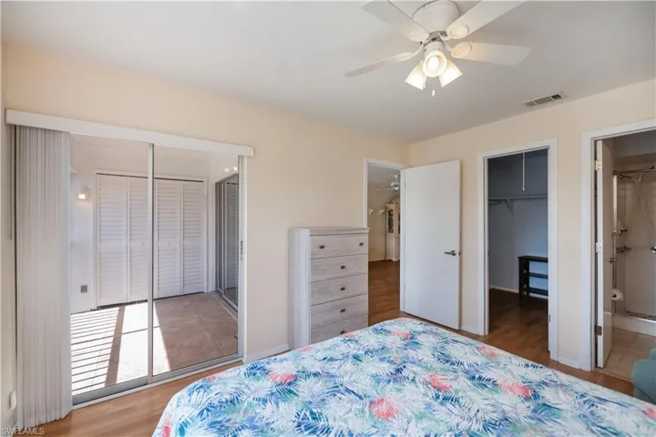 Bedroom featuring connected bathroom, light wood-style floors, ceiling fan, and a walk in closet