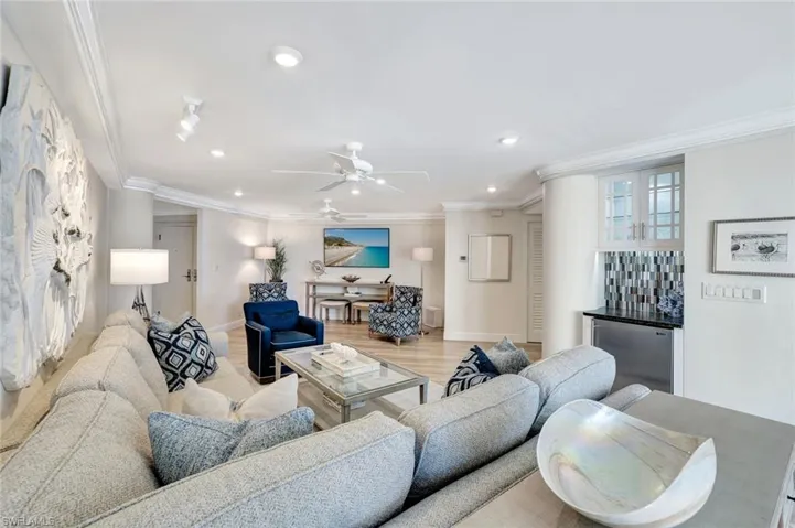 Living area with baseboards, a dry bar, ornamental molding, and recessed lighting