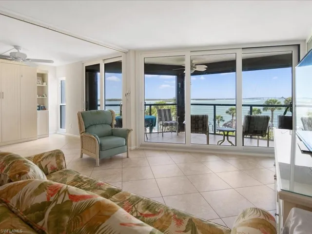 Living room featuring light tile patterned floors, a wall of windows, and ceiling fan