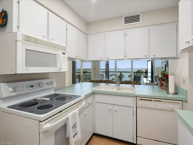 Kitchen featuring white cabinetry, sink, white appliances, and kitchen peninsula