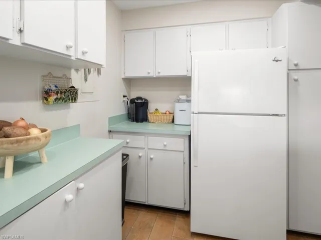 Kitchen with light wood-type flooring, white fridge, and white cabinets