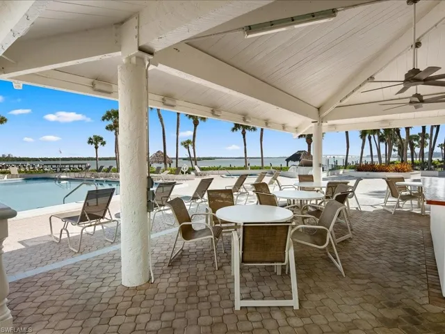 View of patio with a water view, ceiling fan, and a community pool