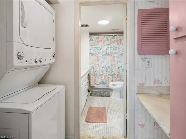 Washroom with tile patterned floors and stacked washer / dryer