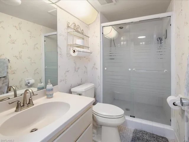 Bathroom with vanity, a shower with shower door, and toilet