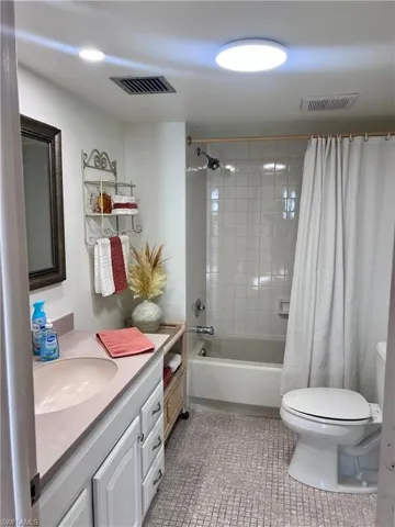 Full bath with shower / bathtub combination with curtain, vanity, and light tile patterned floors
