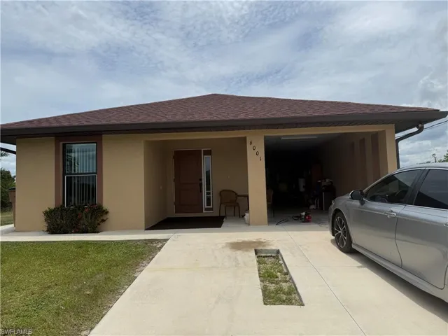 Tan stucco exterior with brown trim, featuring a dark brown front door with sidelight