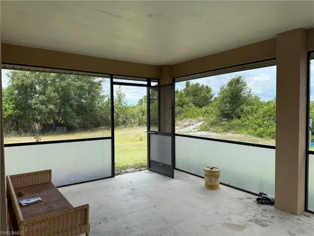 Screened lanai featuring a concrete floor, opaque lower screening, and a screened entry door