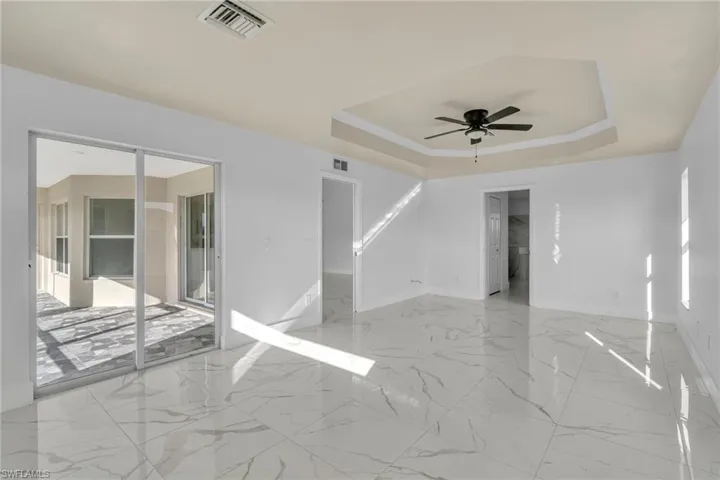 Empty room featuring a raised ceiling and a ceiling fan