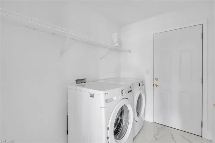 Laundry room featuring washer and dryer and marble finish floors