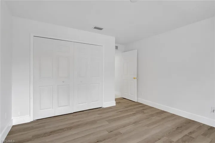 Unfurnished bedroom with wood finished floors and a closet