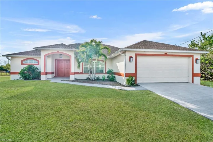 View of front of house with stucco siding, concrete driveway, and a front lawn
