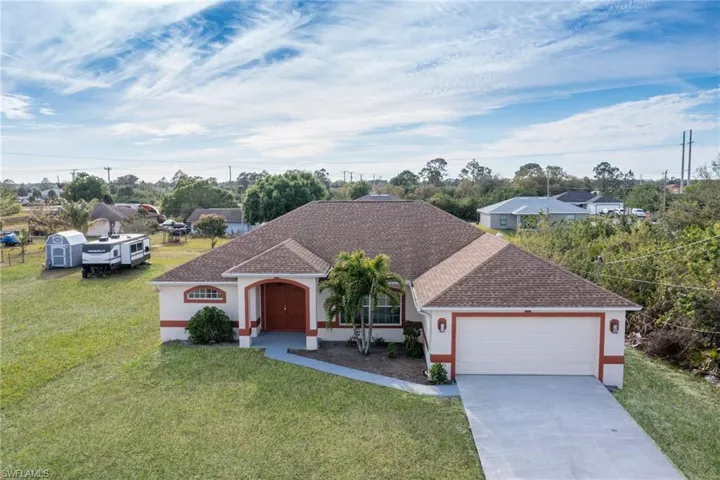 View of front of home with roof with shingles, a front lawn, stucco siding, concrete driveway, and a garage