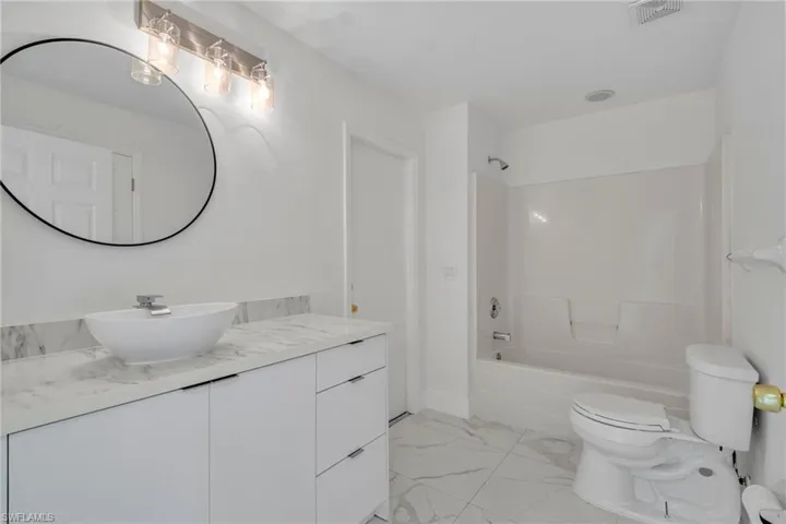 Full bathroom with vanity, shower / bathtub combination, and light marble finish flooring