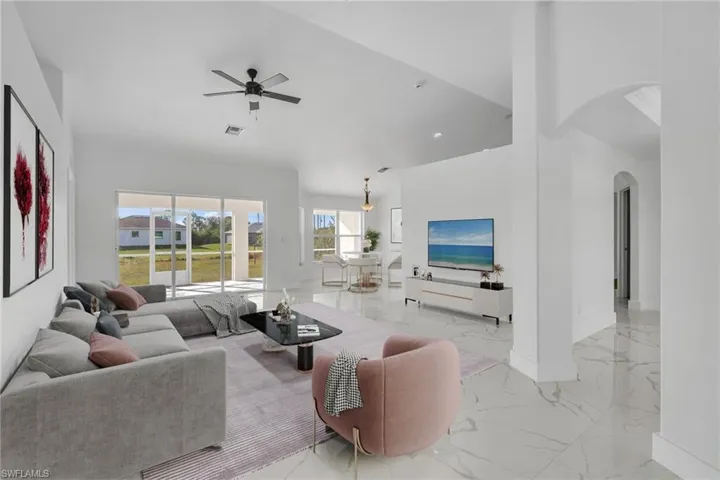 Living area featuring arched walkways, light marble finish floors, a towering ceiling, a ceiling fan, and recessed lighting
