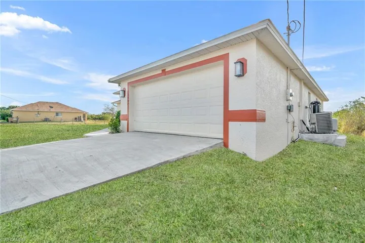 View of home's exterior featuring stucco siding, driveway, and a lawn