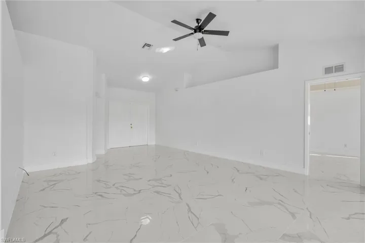 Spare room featuring a ceiling fan, high vaulted ceiling, and light marble finish floors