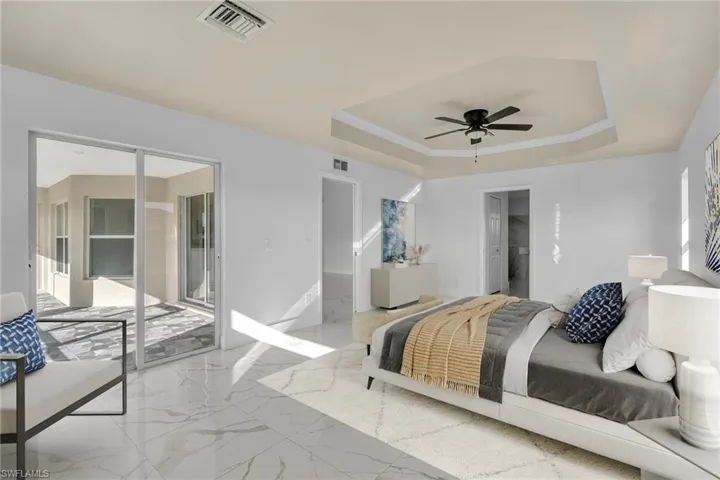 Bedroom with access to outside, a tray ceiling, a ceiling fan, a spacious closet, and marble finish flooring