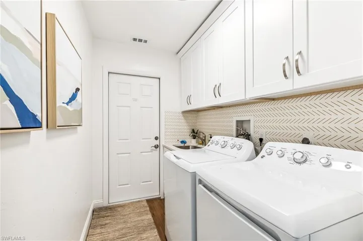 Laundry area featuring cabinet space, washer and dryer, and wood finished floors