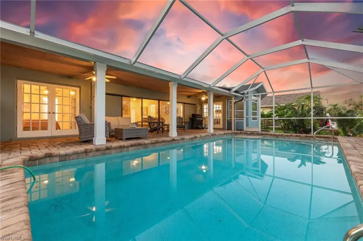 Pool at dusk with an outdoor pool, french doors, an outdoor living space, and a patio area