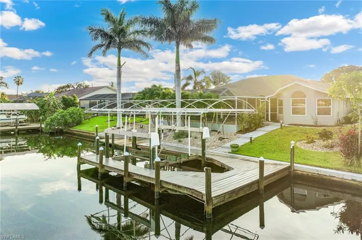 Dock with boat lift, a lawn, a lanai, and a water view