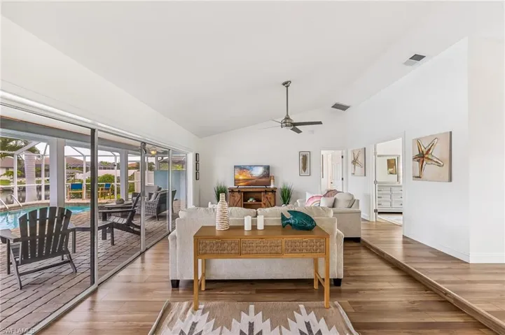 Living room featuring ceiling fan, wood finished floors, and high vaulted ceiling