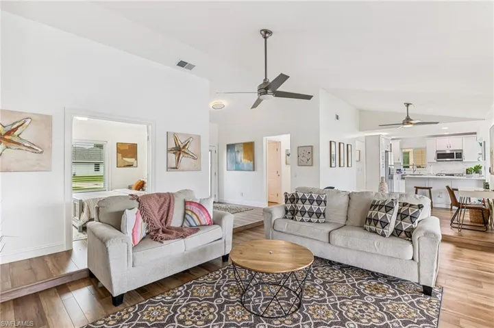 Living area with ceiling fan, light wood-style floors, and high vaulted ceiling