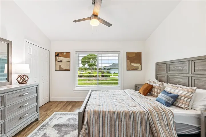 Bedroom with lofted ceiling, light wood-type flooring, a ceiling fan, and a closet