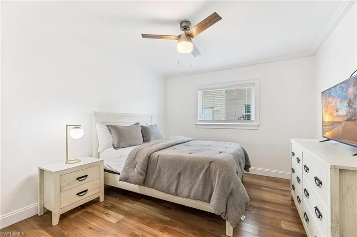 Bedroom with ornamental molding, wood finished floors, and a ceiling fan