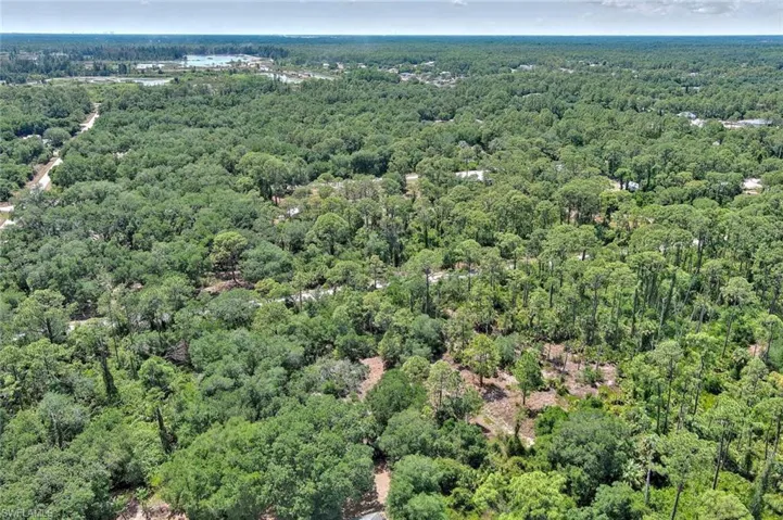 Aerial view of property and surrounding area with a heavily wooded area