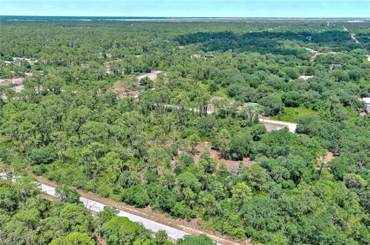 Aerial view of property and surrounding area featuring a forest