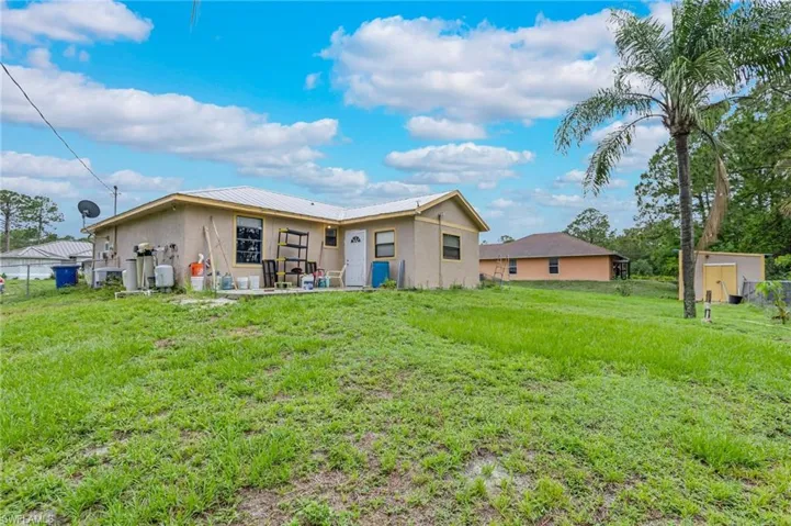 Rear view of property with stucco siding, a lawn, and a metal roof