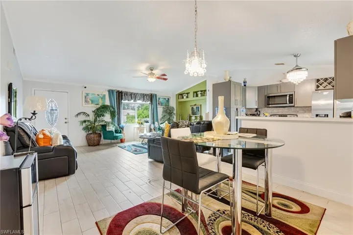Dining area with vaulted ceiling, a ceiling fan, a chandelier, and wood tiled floors