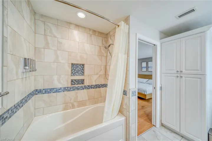 Bathroom featuring connected bathroom, shower / bath combination with curtain, and recessed lighting