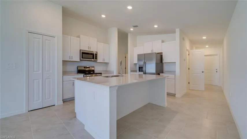 Kitchen with a kitchen island with sink, white cabinetry, stainless steel appliances, and sink