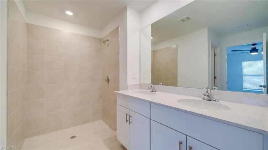 Bathroom featuring tile patterned flooring, vanity, ceiling fan, and a tile shower