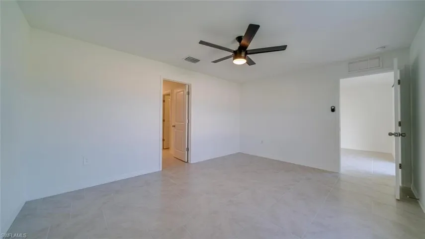 Empty room with ceiling fan and light tile patterned floors
